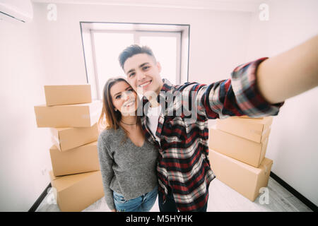 Gerne attraktive junge Paar bewegt, eine selfie, Kuscheln und lächelnd, während Sitzen unter Kartons Stockfoto