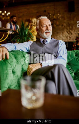 Portrait von eleganten älterer Mann sitzt auf der Couch in einer Bar Stockfoto