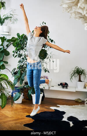 Ausgelassene junge Frau in einem Zimmer springen Stockfoto