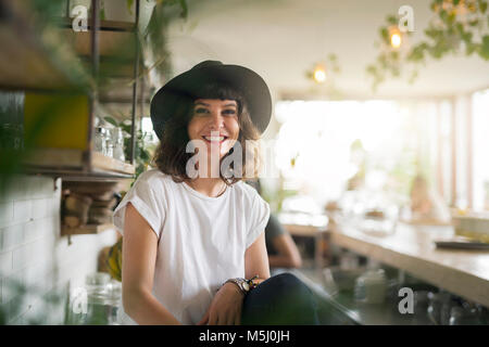 Portrait von Frau mit schwarzem Hut hinter der Bar in einem Cafe Stockfoto