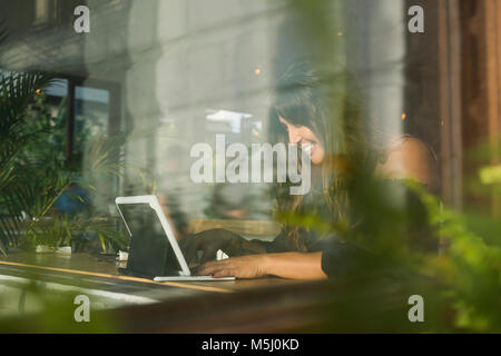 Lächelnde Frau mit Tablette in ein Café hinter Fenster Stockfoto