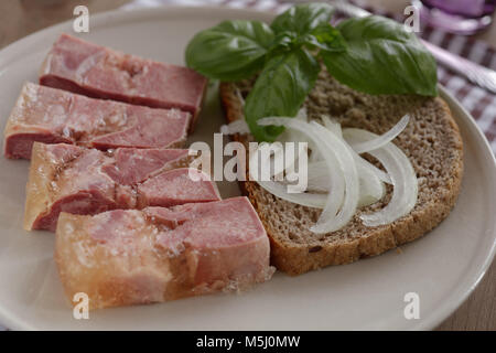 Rinderzunge in Aspik mit Basilikum und Zwiebeln auf der Scheibe Brot Stockfoto