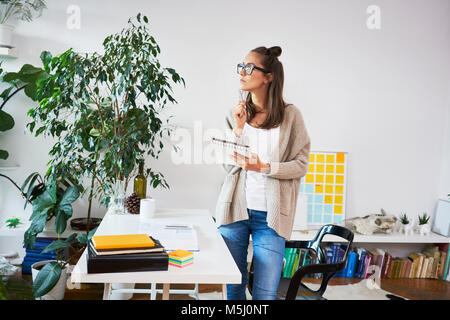 Junge Frau im Werkraum holding Notepad Stockfoto