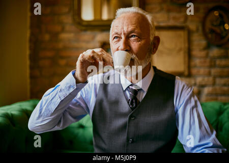 Elegante älterer Mann trinkt Kaffee in einem Cafe Stockfoto