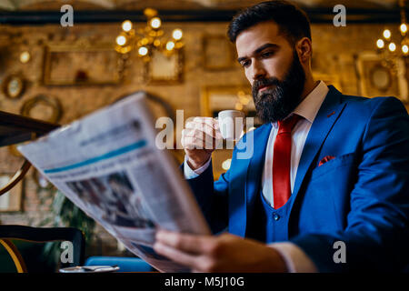 Eleganten mann Kaffee trinken und lesen Zeitung in einem Cafe Stockfoto