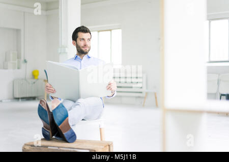 Geschäftsmann sitzt im Leeren loft Office holdig Großer Ordner Stockfoto