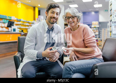 Portrait von lächelnden Apotheker und Kunde mit Blutzucker Messgerät in der Pharmazie Stockfoto