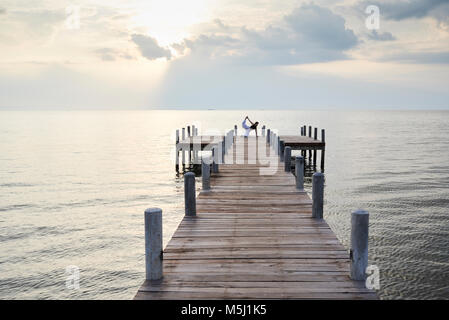 Yoga Lehrer in Bird Dog Position gegen den Sonnenuntergang und das Meer. Kep, Kambodscha. Stockfoto