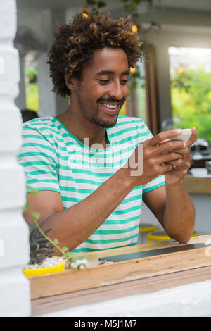 Lächelnd Mann sein Smartphone Kontrolle an der Bar in einem Cafe Stockfoto