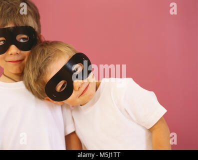 Portrait von zwei lächelnde kleine Jungen mit schwarzen Auge Masken Stockfoto