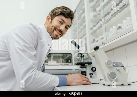 Portrait von lächelnden Mann mit Mikroskop im Labor Stockfoto