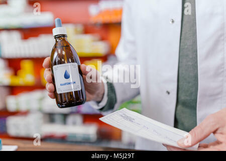 Apotheker halten sie Flasche und Rezept in Apotheke Stockfoto