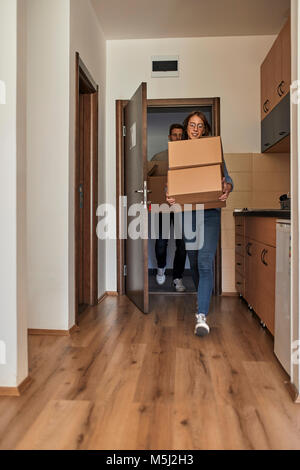 Junge Frauen und der Mann, der Kartons in einen Raum Stockfoto