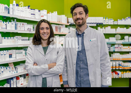 Portrait von zwei lächelnde Apotheker an Regal mit Medikament in der Apotheke Stockfoto
