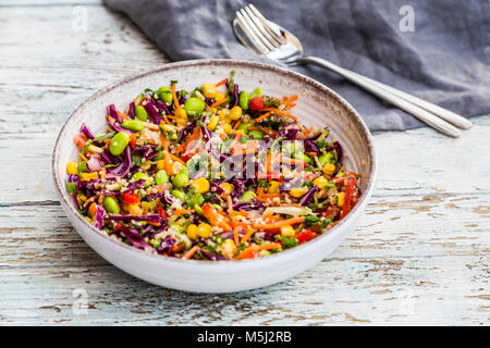 Quinoa Salat mit edamame, Mais, carott, Tomaten, Paprika, Zwiebeln in eine Schüssel geben. Stockfoto