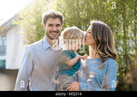 Happy Family im Garten vor der Bambus Pflanzen mit Mutter küssen Sohn Stockfoto