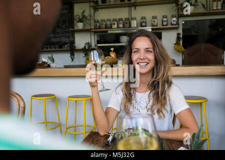 Lächelnde Frau mit einem Glas Wein bei man in einem Café auf der Suche Stockfoto