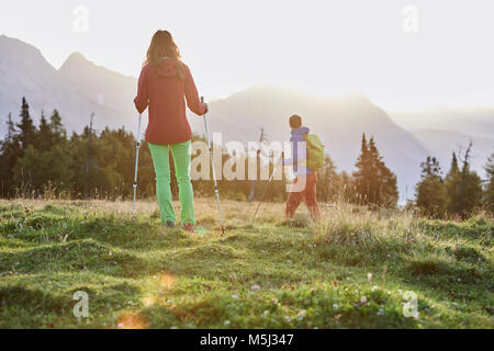 Österreich, Tirol, Mieminger Plateau, zwei Wanderer auf almwiese bei Sonnenaufgang Stockfoto