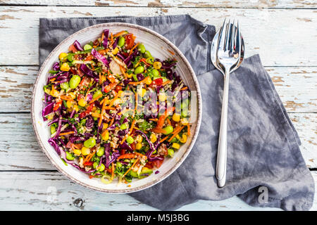 Quinoa Salat mit edamame, Mais, carott, Tomaten, Paprika, Zwiebeln in eine Schüssel geben. Stockfoto