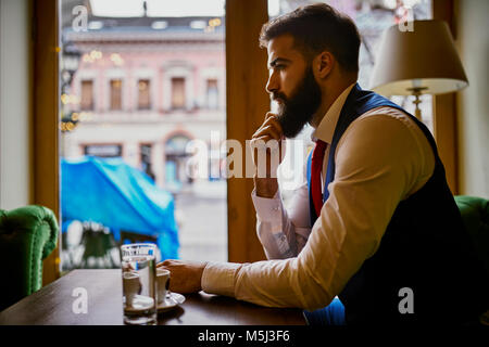 Nachdenklich modischen jungen Mann in einem Café sitzen Stockfoto