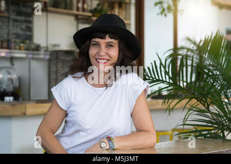 Portrait von Frau mit schwarzem Hut hinter der Bar in einem Cafe Stockfoto