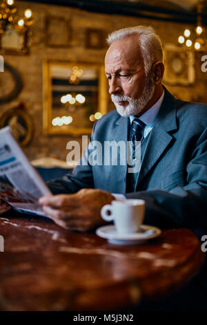 Elegante älterer Mann lesen Zeitung in einem Cafe Stockfoto