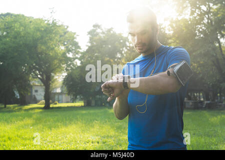 Runner im städtischen Park seinem smartwatch Stockfoto