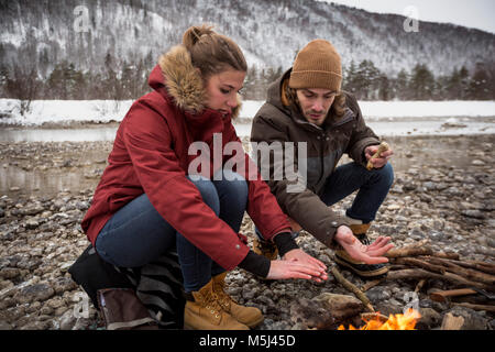 Paar auf eine Reise im Winter wärmende Hände am Lagerfeuer. Stockfoto