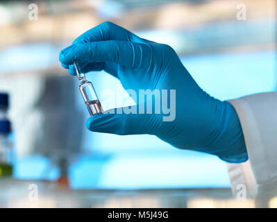 Wissenschaftler halten eine Durchstechflasche mit einer Flüssigkeit im Labor Stockfoto