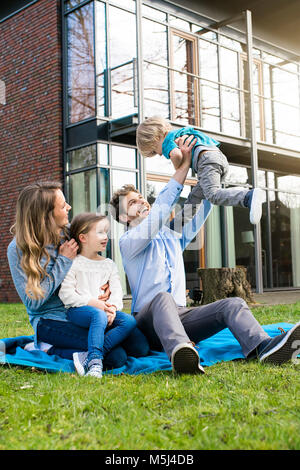 Happy Family auf die Decke im Garten vor ihrem Haus mit Vater, Sohn litfting Stockfoto