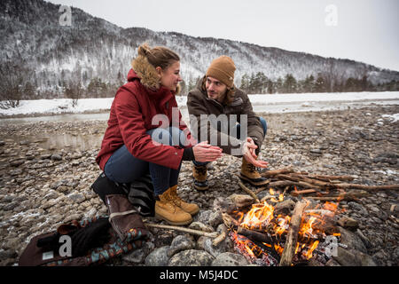 Paar auf eine Reise im Winter wärmende Hände am Lagerfeuer. Stockfoto