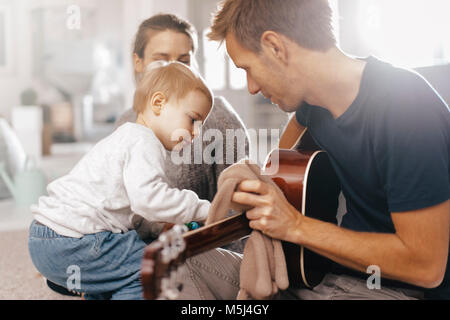 Kleines Mädchen Prüfung der Vater Gitarre zu Hause Stockfoto