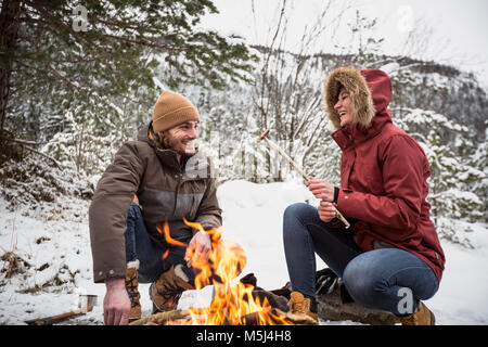 Glückliches Paar auf einer Reise im Winter eine Pause am Lagerfeuer. Stockfoto