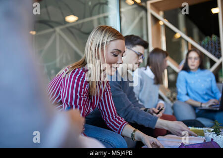 Eine Gruppe von Freunden zusammen sitzen in einem Café zu diskutieren Dokumente Stockfoto