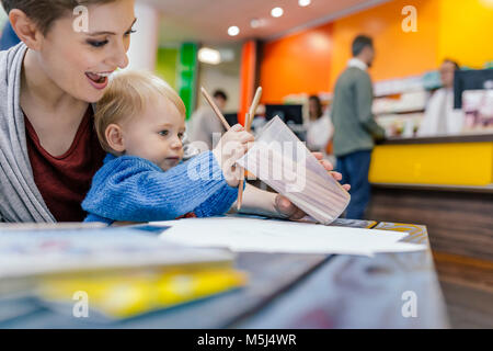 Kleiner Junge mit der Mutter Zeichnung am Tisch in der Pharmazie Stockfoto
