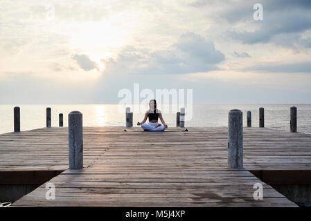 Yoga Lehrer Üben der Meditation in einer Lotus Position gegen den Sonnenuntergang und das Meer. Kep, Kambodscha. Stockfoto