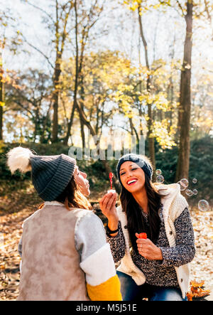 Zwei schöne Frauen Spaß mit Seifenblasen in herbstlicher Wald Stockfoto