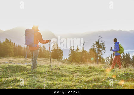 Österreich, Tirol, Mieminger Plateau, zwei Wanderer auf almwiese bei Sonnenaufgang Stockfoto