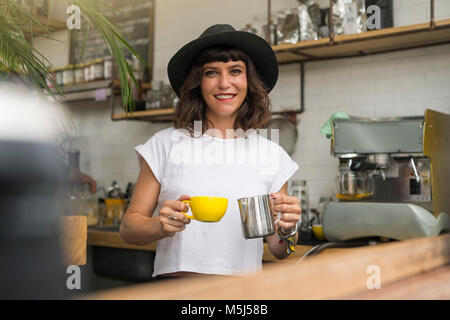 Portrait von Frau mit schwarzem Hut hinter der Bar einen Kaffee vorbereiten Stockfoto