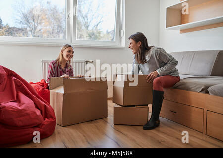 Zwei glückliche junge Frauen Auspacken der Kartons in einem Zimmer Stockfoto