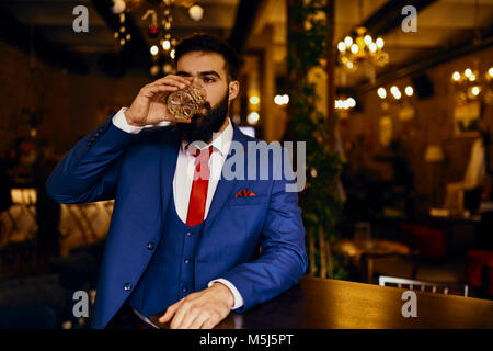 Eegant junger Mann in einer Bar trinken aus Zuhaltung Stockfoto