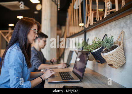 Junge Frau und ein Mann in einem Café mit Laptops Stockfoto