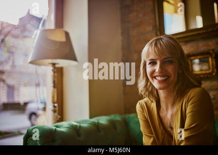 Portrait von lächelnden elegante Frau sitzt auf einer Couch Stockfoto