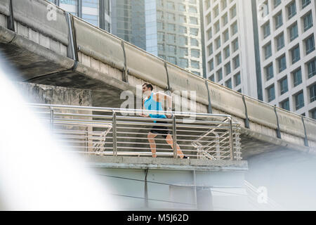 Läufer in Blue Fitness shirt über moderne Brücke läuft Stockfoto