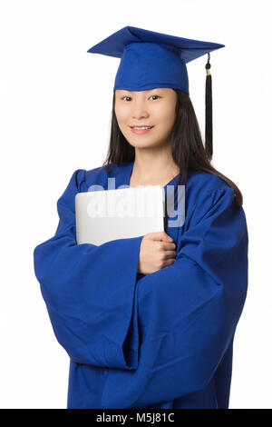 Schöne asiatische Frau mit einem Computer, während eine blaue Graduierung Kleid auf weißem Hintergrund tragen Stockfoto