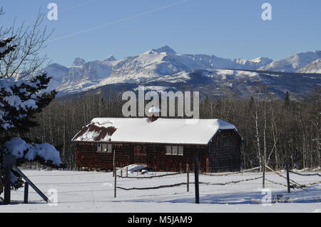 Eine alte historische Hütte, mit einem herrlichen Schnee auf die Berge in der Ferne Stockfoto