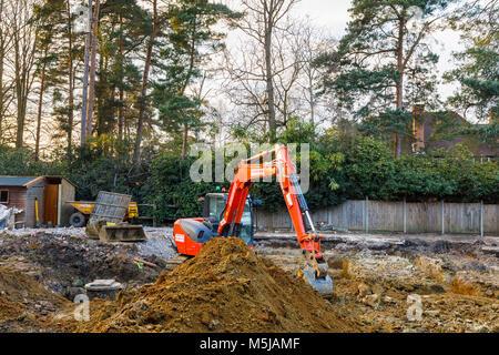 Große orange schwere Anlage mechanische Bagger auf einer Baustelle geparkt nach graben Ausgrabungen für die Grundlagen einer neuen Wohnanlage Stockfoto