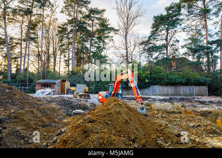 Große orange schwere Anlage mechanische Bagger auf einer Baustelle geparkt nach graben Ausgrabungen für die Grundlagen einer neuen Wohnanlage Stockfoto