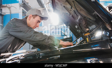 Mechaniker männlichen im Auto garage prüfen die Motorhaube des Autos für Luxus-SUV Stockfoto