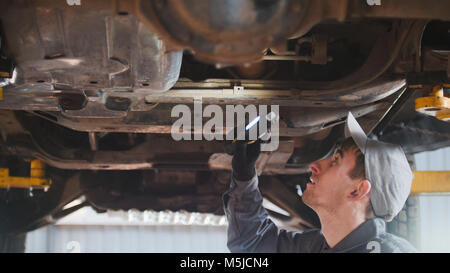 Mechaniker ist Kontrolle der Unterseite des Autos in der Garage automobile Service, Nahaufnahme Stockfoto